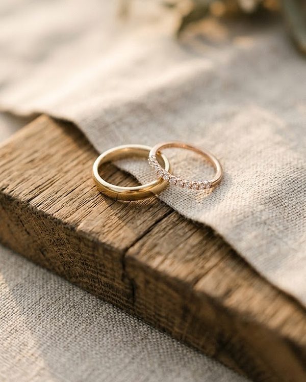 Anillos de boda dorados sobre una viga de madera y lino