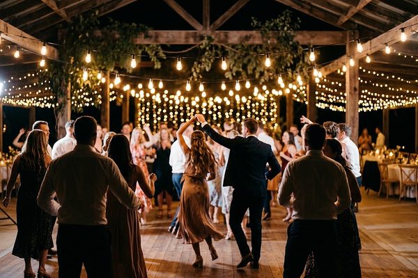 Novios bailando rodeados de invitados bajo guirnaldas de luces